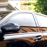A luxury vehicle parked in a brightly lit area. The car's windows are tinted, so the interior is hidden.