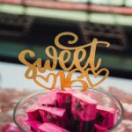 Home 7 Three glass containers filled with candies, including gummy bears and Starbursts, with a "Sweet 16" topper in the center jar.